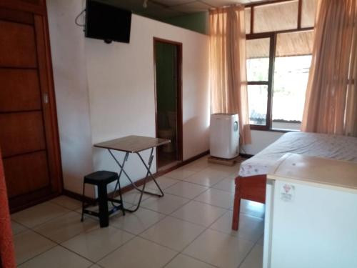 1 dormitorio con cama, mesa y ventana en Hospedaje Casa Amazónica Iquitos, en Iquitos