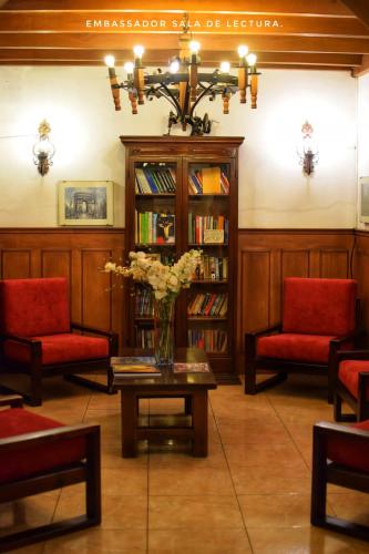 a library with red chairs and a vase of flowers on a table at Hotel Ambassador in Quito