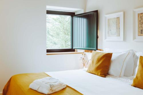 a white bed in a room with a window at Oliveiras Village — Agroturismo in Amarante
