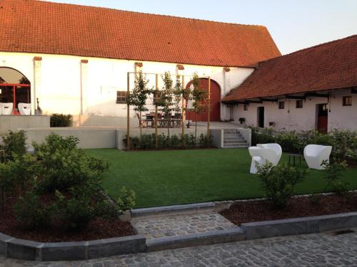 a house with a yard with two white chairs at B&B Hof ter Kwaremont in Kluisbergen