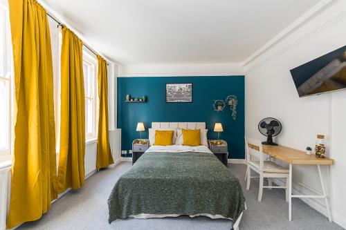 a bedroom with a bed and a desk and yellow curtains at Verv Brick Lane in London