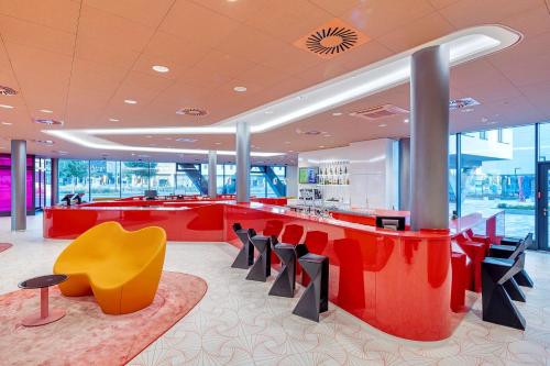 a lobby with a red counter and a yellow chair at prizeotel Vienna-City in Vienna