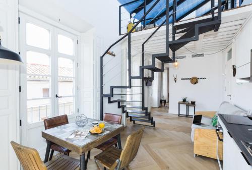 a dining room with a table and chairs and a staircase at Malagaflat NoMeOlvides in Málaga