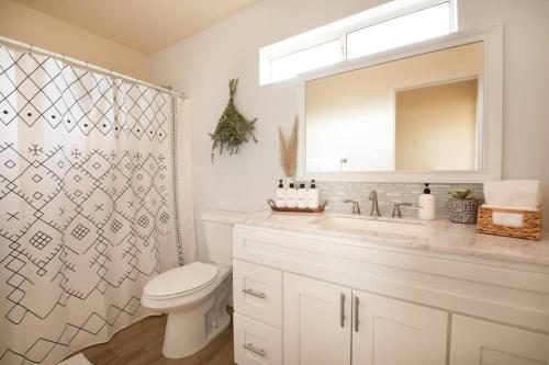 a bathroom with a toilet and a sink and a mirror at Cryptic Cabin-Tranquil Bohemian Getaway w/Hot Tub in Yucca Valley