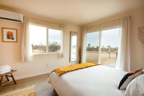 1 dormitorio con cama grande y ventana grande en Cryptic Cabin-Tranquil Bohemian Getaway w/Hot Tub, en Yucca Valley