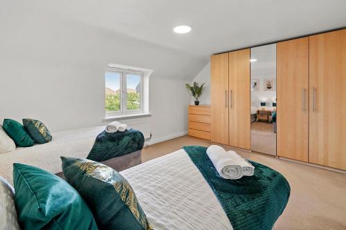 a bedroom with two beds with green pillows at Townhouse in Dartford sleeps 8 with free parking in Dartford