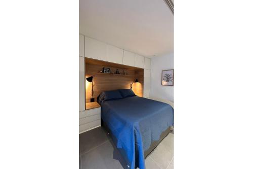 - une chambre avec un lit bleu et une tête de lit en bois dans l'établissement Estúdio Moderno com Vista Oceânica, à Rio de Janeiro