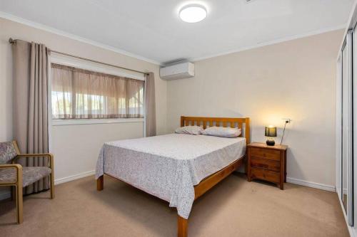 a bedroom with a bed and a chair and a window at 4-Bedroome home, new bathrooms and close to town in Kalgoorlie