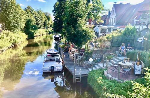 een boot ligt aangemeerd in een rivier naast een restaurant bij Knuffelkamer über der Gracht in Friedrichstadt