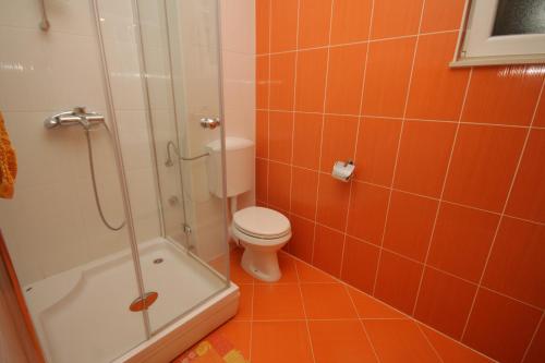 een oranje badkamer met een toilet en een douche bij Apartments by the sea Stari Grad, Hvar - 8704 in Stari Grad