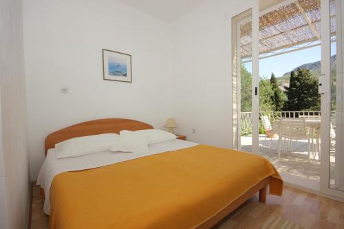 a white bedroom with a bed and a balcony at Apartments and rooms by the sea Srebreno, Dubrovnik - 8957 in Mlini