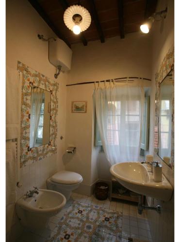 a bathroom with two sinks and a toilet and a mirror at Villa Toppani Del Sodo in Cortona