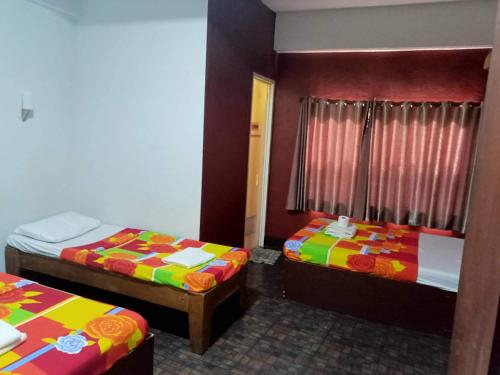 a room with two beds with colorful sheets at Antonio's Pension House in Dipolog