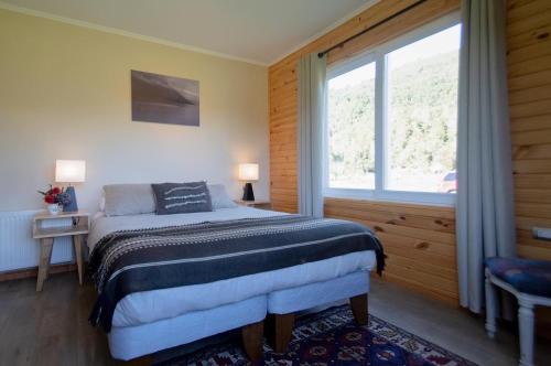 a bedroom with a bed and a large window at Vuelta al Sur in Puelo