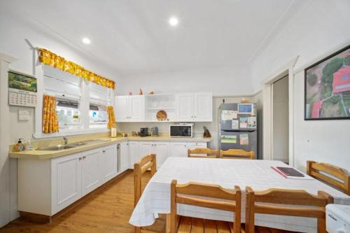 a kitchen with white cabinets and a table with chairs at "Mansfield" Cottage Barrington QUALITY HOLIDAY ACCOMMODATION in Barrington