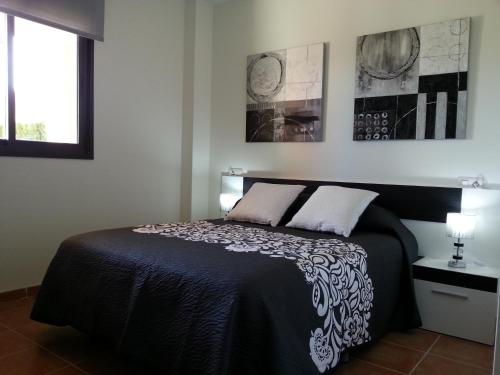 a bedroom with a black bed with two pillows at Apartamento unifamiliar Golf Vera urb privada y tranquila in Vera