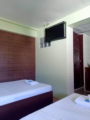 a room with two beds and a tv on the wall at Antonio's Pension House in Dipolog