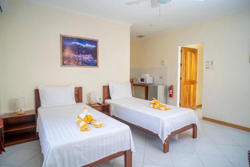 a bedroom with two beds with white sheets and yellow bows at Alona Austria Resort in Panglao