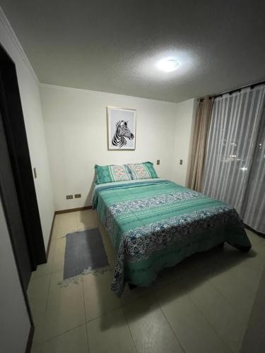 1 dormitorio con 1 cama con edredón verde en Fantástico departamento a pasos de playa cavancha con estacionamiento en Iquique