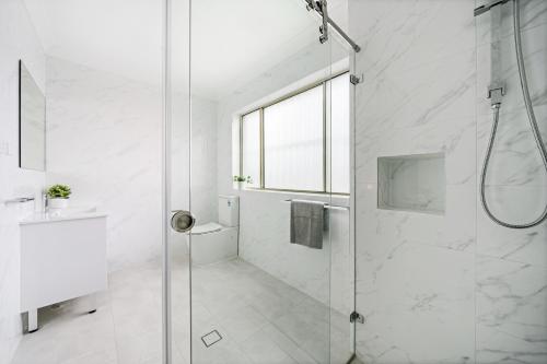 a white bathroom with a shower and a sink at Burwood new 2 bedroom 2 bathroom apartment in Sydney