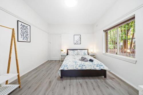 a white bedroom with a bed and a window at Burwood new 2 bedroom 2 bathroom apartment in Sydney