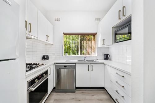 a white kitchen with white cabinets and a window at Burwood new 2 bedroom 2 bathroom apartment in Sydney