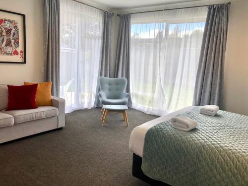 een slaapkamer met een bed, een stoel en een raam bij Timeout @ Taupo - Lake Views in Taupo