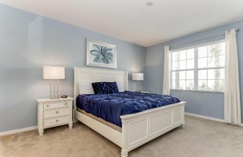 - une chambre avec un lit aux murs bleus et une fenêtre dans l'établissement Beautiful 9 bedroom pool home located in the Solterra Resort! home, à Davenport