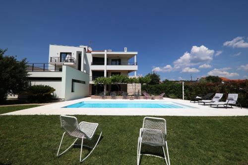 ein Haus mit einem Pool und zwei Gartenstühlen in der Unterkunft Holiday house with a swimming pool Zadar - Diklo, Zadar - 15336 in Zadar