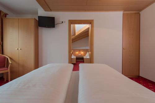 a bedroom with a white bed and a mirror at Hotel Garni Hochgruber in Brunico