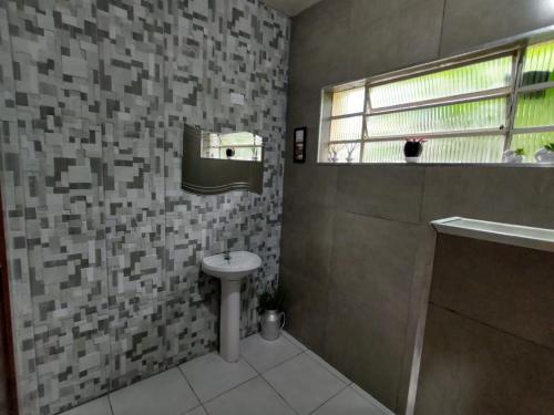 a bathroom with a sink and a toilet and a window at Chácara em Guararema Brasil in Guararema