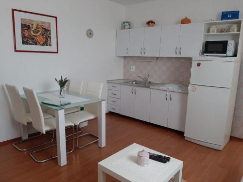 a kitchen with white cabinets and a table and a table and chairs at Apartments with parking space Cizici, Krk - 15415 in Malinska