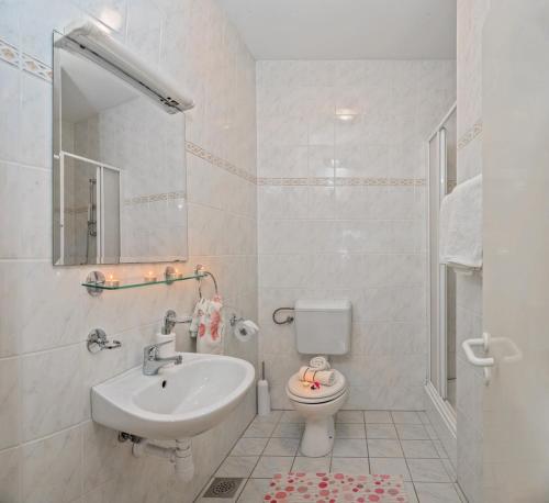 a white bathroom with a sink and a toilet at Apartments and rooms with parking space Bol, Brac - 15418 in Bol