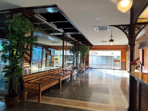 a lobby with benches and plants in a building at River Grand Hotel in Hat Yai