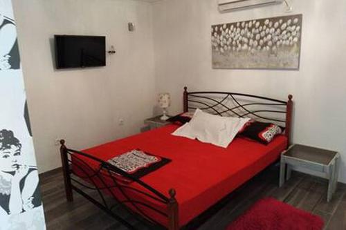 a bedroom with a red bed with a tv on the wall at Apartments with WiFi Stari Grad, Hvar - 15464 in Stari Grad