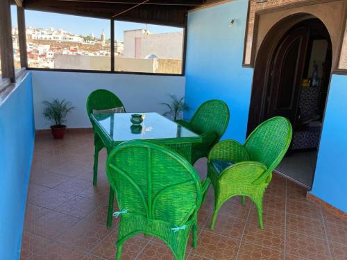 une table et des chaises vertes sur la terrasse dans l'établissement TanjaLucia Hostel, à Tanger