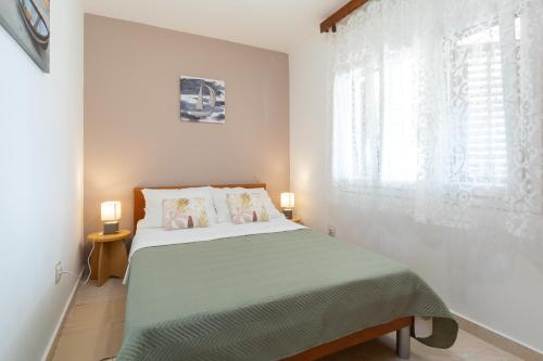a white bedroom with a bed and a window at Family friendly house with a parking space Prizba, Korcula - 15468 in Prizba