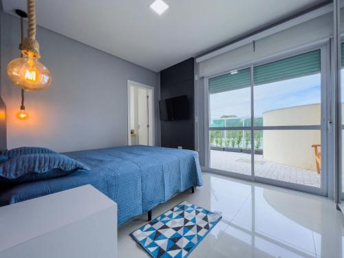 1 dormitorio con cama azul y ventana grande en Costa Mexicana, en Bombinhas