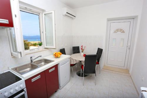 a kitchen with a sink and a table with chairs at Apartments by the sea Drvenik Mali (Drvenik) - 15535 in Drvenik Mali