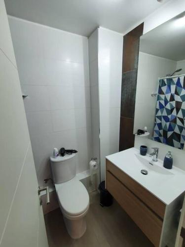 ein weißes Badezimmer mit Toilette und Waschbecken in der Unterkunft Bello depto en Dunas de Concon in Concón