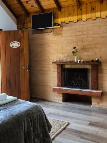 a room with a fireplace and a tv on a wall at Terrace house in Monte Verde