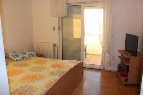 a bedroom with a bed and a television and a window at Apartments with a parking space Gradac, Makarska - 15628 in Gradac