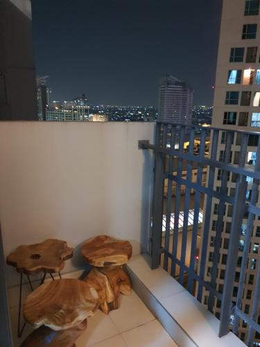 a balcony with two wooden tables and a city skyline at Casa Grande Residence Tower Angelo in Jakarta