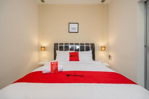 a bed with a red blanket on top of it at RedDoorz near Transmart Kalimalang in Jakarta