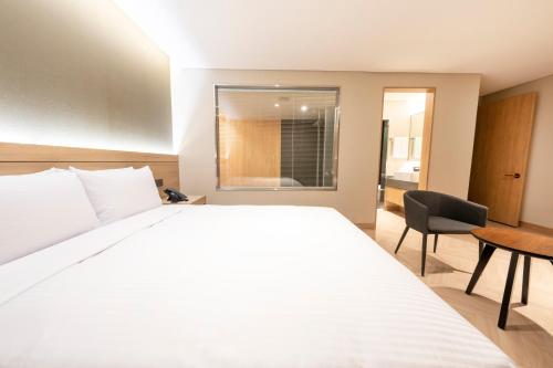 a bedroom with a large white bed and a desk at Hotel Foret The Spa in Busan