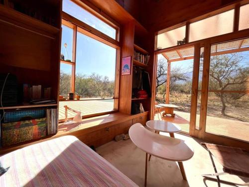 een kamer met een bed en twee tafels en ramen bij Mandala Tiny House, Traslasierra. in Yacanto