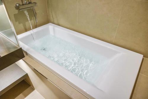 a bath tub with water in it in a bathroom at Hotel Foret The Spa in Busan