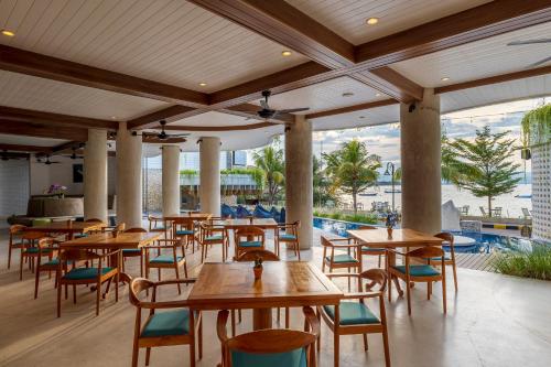 a restaurant with wooden tables and chairs and a pool at The Beach House Resort in Gili Trawangan