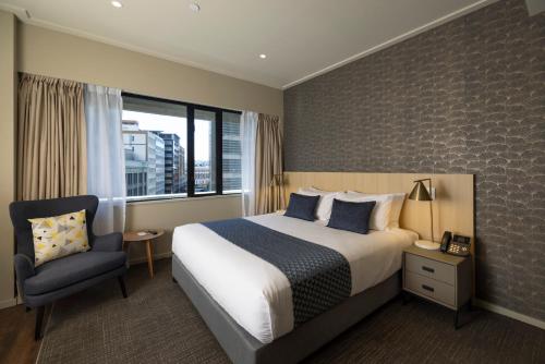 a hotel room with a bed and a chair at Quest 256 Lambton in Wellington