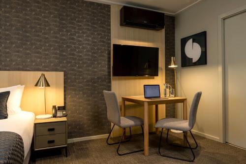 a hotel room with a bed and a desk with a laptop at Quest 256 Lambton in Wellington
